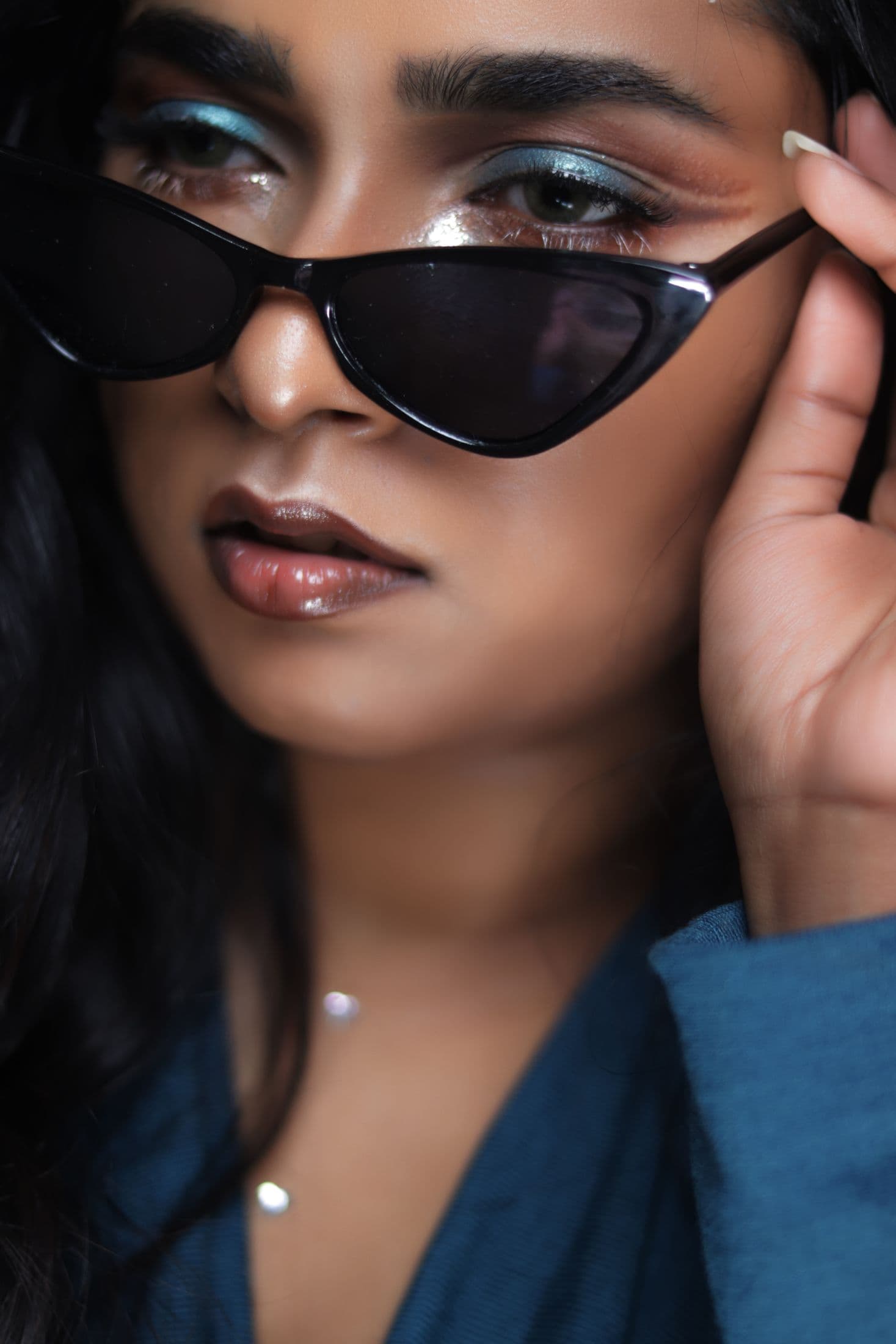 Beauty close-up with blue shimmer eyes, glossy lips and black sunglasses