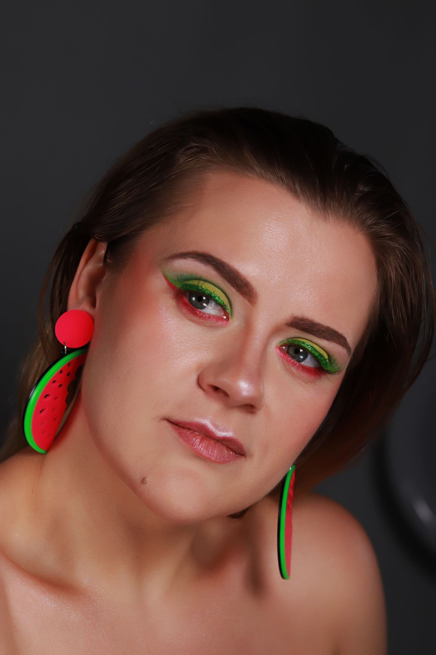 Editorial portrait with green and coral eye makeup and watermelon earrings